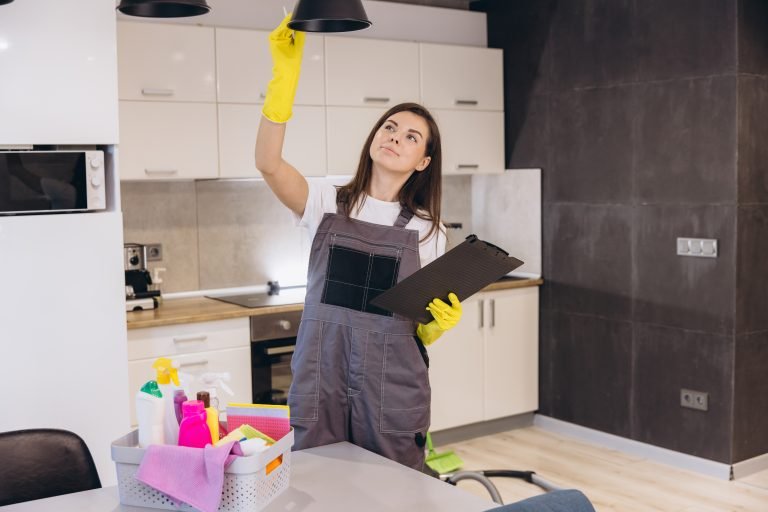 Cleaning lady checking a lamp with checklist in the kitchen